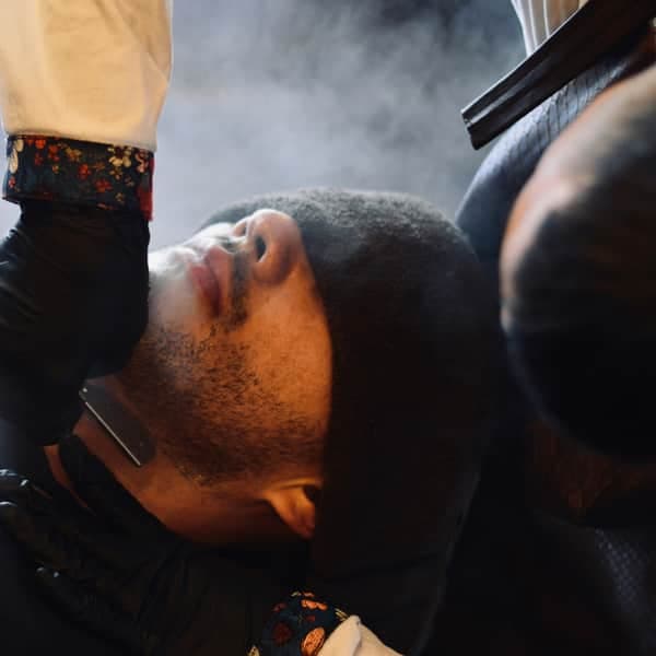A client leaning back for a shave, steam rising