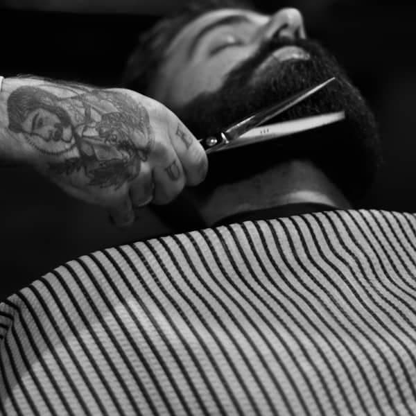 A beard being shaped with scissors, in black and white