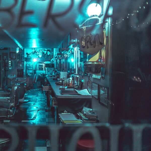 The shop's front window, lit teal, with the chairs inside